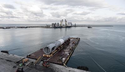 Vorsichtig fahren die elektronisch gelenkten Module mit der empfindlichen Fracht vom Hafengelände auf das wartende Binnenschiff.